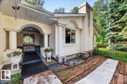 Arched entryway with substantial columns, stucco exterior finish, and a concrete pathway - 