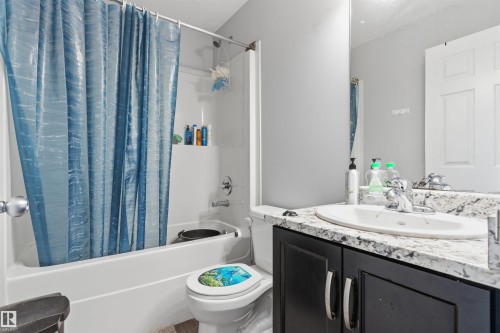 White tub/shower combination, dark wood-finish vanity with silver-tone hardware, white countertop with integrated sink, chrome faucet, and expansive wall mirror - #30 3305 Orchards Link Sw Sw, Edmonton, AB 