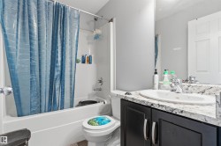 White tub/shower combination, dark wood-finish vanity with silver-tone hardware, white countertop with integrated sink, chrome faucet, and expansive wall mirror - 