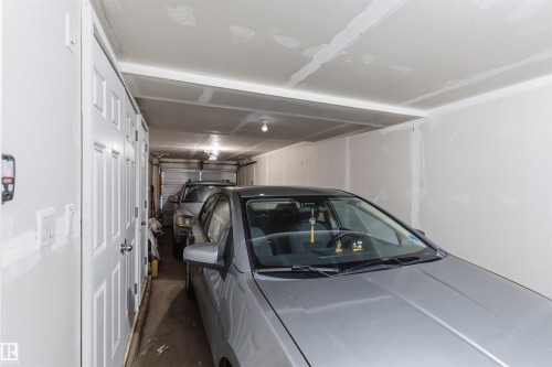 Spacious attached garage featuring epoxy-coated flooring, recessed ceiling lighting, and ample room for multiple vehicles with direct interior access - #30 3305 Orchards Link Sw Sw, Edmonton, AB 