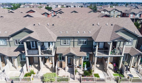 Townhouse exterior featuring individual balconies, gabled rooflines, and front yard fencing - #30 3305 Orchards Link Sw Sw, Edmonton, AB 