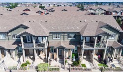 Townhouse exterior featuring individual balconies, gabled rooflines, and front yard fencing - 