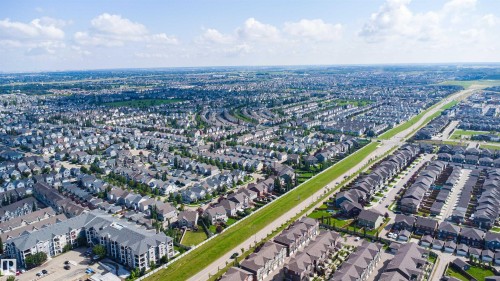 Expansive residential area featuring a variety of housing types, broad road infrastructure, and distant green spaces - #30 3305 Orchards Link Sw Sw, Edmonton, AB 