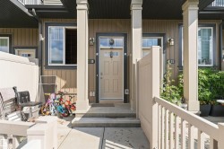 Entry featuring a beige paneled door, exterior wall sconces, and a window with white trim - 