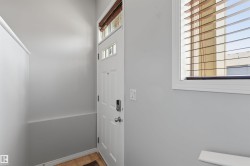Entry with a white paneled door, transom windows, and an adjacent window with wood-finish blinds - 