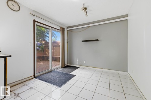 White tile flooring, sliding glass door, built-in shelving, wood deck, and exposed ceiling light fixture - 3515 43 Avenue Nw, Edmonton, AB -  With Exterior