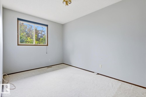Light gray walls with a window featuring dark wood-finish trim, white carpet flooring, and a ceiling-mounted light fixture - 3515 43 Avenue Nw, Edmonton, AB - Indoor Photo Showing Other Room