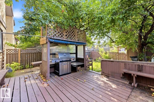 Wood-finish deck with built-in seating, featuring a dedicated outdoor grilling station, and surrounding mature trees - 3515 43 Avenue Nw, Edmonton, AB - Outdoor With Deck Patio Veranda