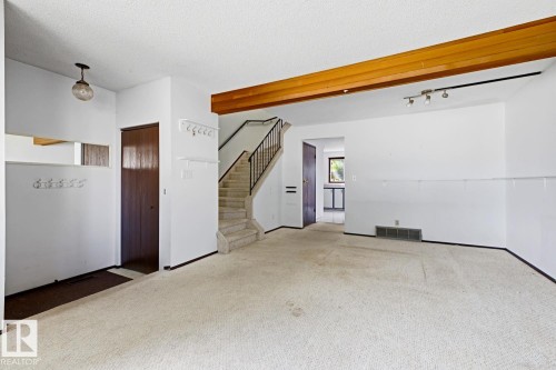 Exposed wood beam ceiling, track lighting, carpeted flooring, staircase with metal railing, and a built-in wall niche - 3515 43 Avenue Nw, Edmonton, AB - Indoor