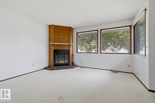 Corner fireplace with wood surround and mantel - 3515 43 Avenue Nw, Edmonton, AB - Indoor Photo Showing Other Room With Fireplace