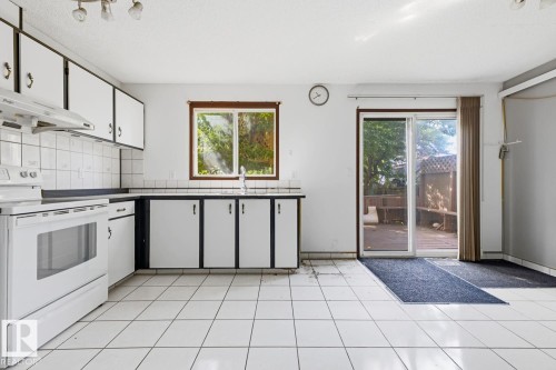 Kitchen with white tile flooring, white upper and lower cabinetry, white tile backsplash, and a window above the sink - 3515 43 Avenue Nw, Edmonton, AB - Indoor Photo Showing Kitchen