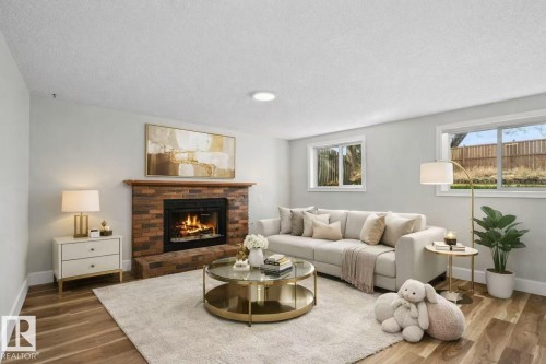 Brick fireplace with hearth, wood-finish flooring, recessed lighting, and multiple windows - 4209 25 Avenue Nw, Edmonton, AB - Indoor Photo Showing Living Room With Fireplace