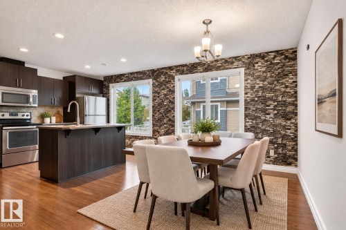 Wood-finish flooring, recessed lighting, and a kitchen island with an undermount sink and gooseneck faucet - #69 3625 144 Av Nw, Edmonton, AB - Indoor