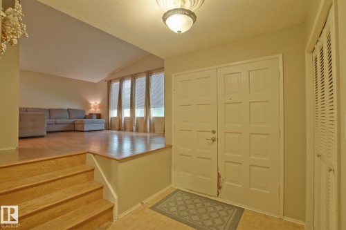 Entryway featuring a decorative ceiling light fixture, paneled double doors, and an adjacent louvered closet - 18107 89 Avenue Nw, Edmonton, AB - Indoor Photo Showing Other Room