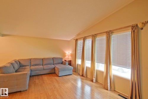 Wood-finish flooring complemented by a series of windows with horizontal blinds - 18107 89 Avenue Nw, Edmonton, AB - Indoor Photo Showing Living Room