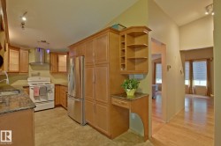 Kitchen featuring extensive wood-finish cabinetry, stainless steel refrigerator, white range, and stone countertops - 
