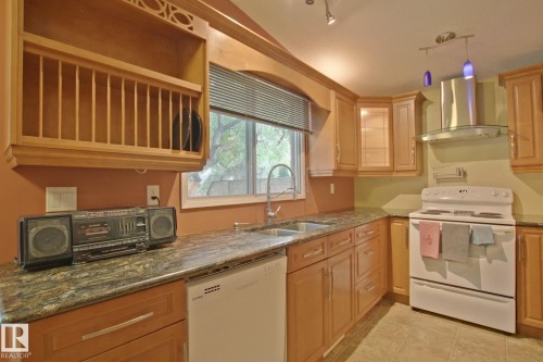 Recessed lighting, wood cabinetry, built-in dishwasher, stainless steel range hood, and tile flooring - 18107 89 Avenue Nw, Edmonton, AB - Indoor Photo Showing Kitchen With Double Sink