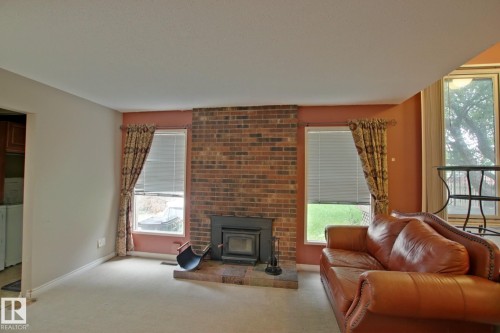 Brick fireplace with a built-in insert, two windows, and carpeting - 18107 89 Avenue Nw, Edmonton, AB - Indoor Photo Showing Living Room With Fireplace