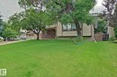 Expansive front lawn with mature trees, stucco exterior, brick accent wall, and a wood privacy fence - 18107 89 Avenue Nw, Edmonton, AB  - Outdoor 