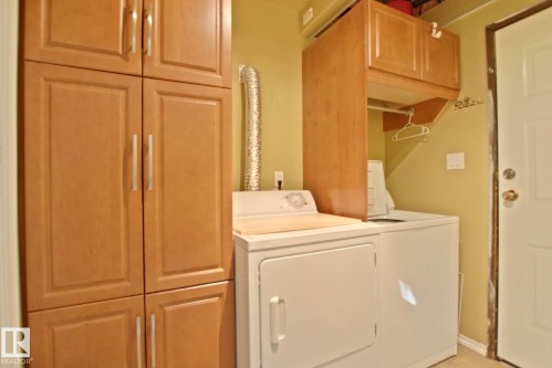 Laundry area featuring a stackable washer and dryer, wood-finish cabinetry, and overhead storage - 18107 89 Avenue Nw, Edmonton, AB - Indoor Photo Showing Laundry Room