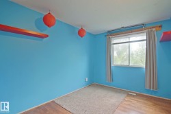Hardwood-finish flooring with partial carpeting, a window with drapery, and a wall-mounted shelf - 