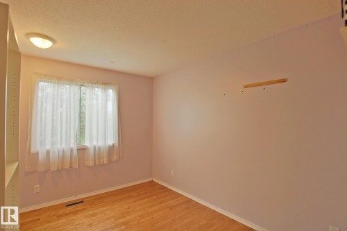 Wood-finish flooring with a flush-mounted ceiling light fixture - 18107 89 Avenue Nw, Edmonton, AB - Indoor Photo Showing Other Room