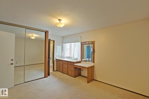 Mirrored closet doors, recessed window, built-in wood-finish vanity with counter space, single-pane window, and overhead lighting - 18107 89 Avenue Nw, Edmonton, AB - Indoor Photo Showing Other Room