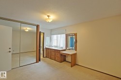Mirrored closet doors, recessed window, built-in wood-finish vanity with counter space, single-pane window, and overhead lighting - 