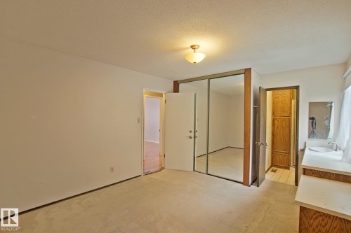 Spacious primary suite featuring a large walk-in closet with mirrored sliding doors, wood-finish flooring throughout, and an ensuite bathroom with vanity and natural lighting - 18107 89 Avenue Nw, Edmonton, AB - Indoor Photo Showing Other Room