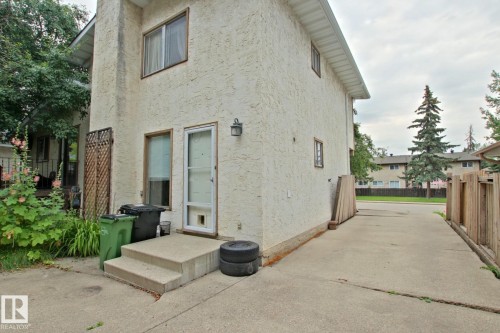 Stucco exterior with concrete steps, a wood privacy fence, and a concrete driveway - 18107 89 Avenue Nw, Edmonton, AB - Outdoor With Exterior