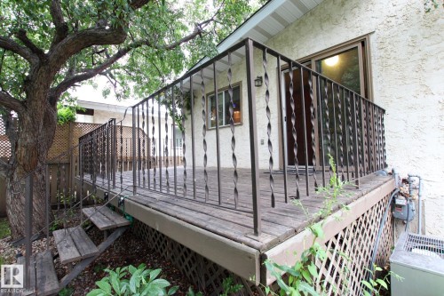 Elevated wood deck with a wrought iron railing, exterior stucco siding, and adjacent mature tree - 18107 89 Avenue Nw, Edmonton, AB - Outdoor With Exterior