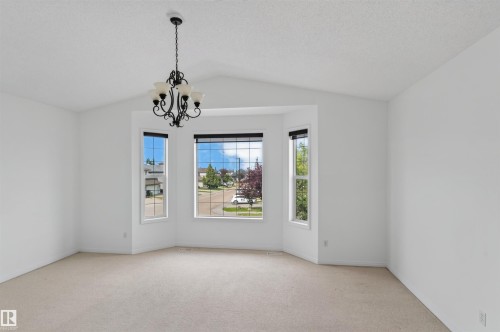 Bay window, vaulted ceiling, chandelier, wall-to-wall carpeting, and white painted walls - 1707 37A Avenue Nw, Edmonton, AB - Indoor Photo Showing Other Room