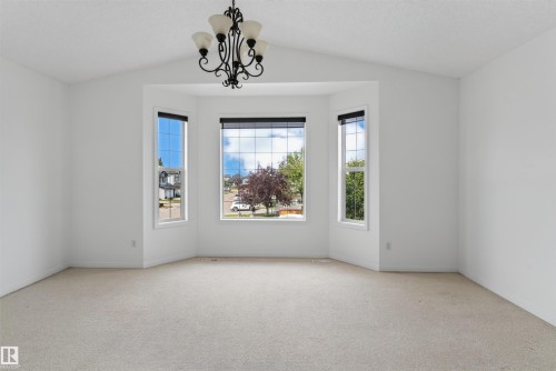 Vaulted ceiling with an ornamental chandelier, bay window with multiple panes, and wall-to-wall carpeting - 1707 37A Avenue Nw, Edmonton, AB - Indoor Photo Showing Other Room