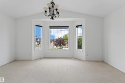 Vaulted ceiling with an ornamental chandelier, bay window with multiple panes, and wall-to-wall carpeting - 