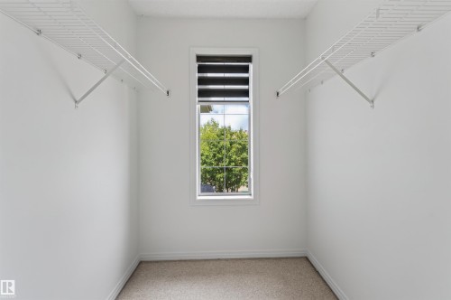 Walk-in closet with white walls, carpeted flooring, window with blinds, and white wire shelving - 1707 37A Avenue Nw, Edmonton, AB - Indoor