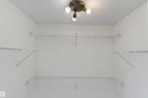 White wire shelving system with multiple tiers, integrated ceiling light fixture, and textured ceiling - 1707 37A Avenue Nw, Edmonton, AB - Indoor With Storage