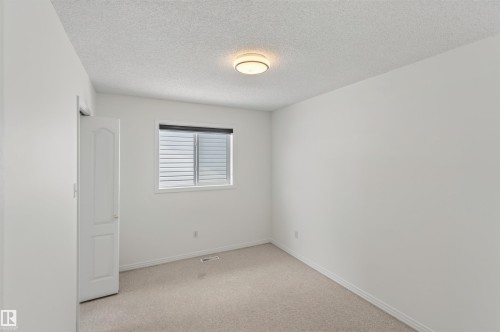 Carpeted flooring, white walls, window with horizontal blinds, flush mount ceiling light, interior door - 1707 37A Avenue Nw, Edmonton, AB - Indoor Photo Showing Other Room