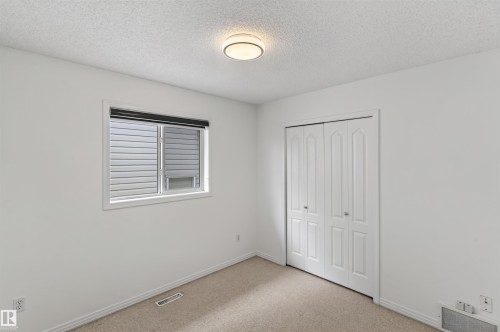 Carpet flooring, white walls, bi-fold closet doors, recessed window, and ceiling-mounted light fixture - 1707 37A Avenue Nw, Edmonton, AB - Indoor