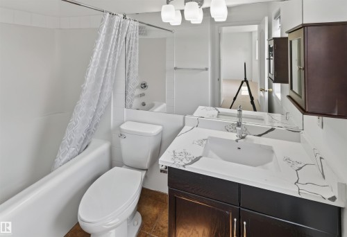 White tub and shower combination with white tile surround - 1707 37A Avenue Nw, Edmonton, AB - Indoor Photo Showing Bathroom