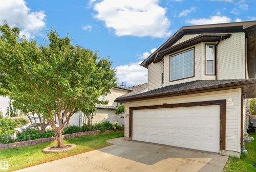 Two-story residential exterior with light-colored siding, attached garage, and a concrete driveway - 1707 37A Avenue Nw, Edmonton, AB - Outdoor