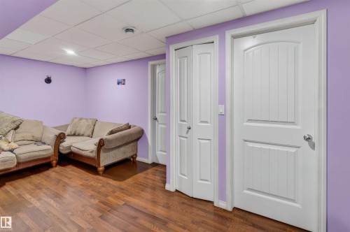 Hardwood-style flooring, drop ceiling with recessed lighting, and three white paneled doors - 1707 37A Avenue Nw, Edmonton, AB - Indoor