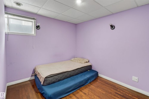 Hardwood-finish flooring, drop ceiling, wall-mounted sconces, and a window with blinds - 1707 37A Avenue Nw, Edmonton, AB - Indoor Photo Showing Bedroom