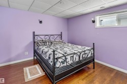 Hardwood-finish flooring with a drop ceiling, wall-mounted sconces, and a window - 