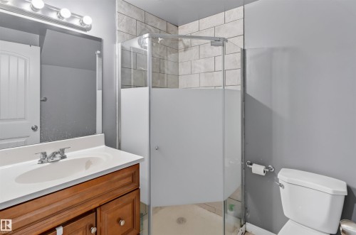 Wood-finish vanity with a white countertop and a chrome faucet - 1707 37A Avenue Nw, Edmonton, AB - Indoor Photo Showing Bathroom