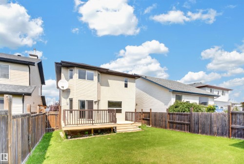 Expansive backyard with a manicured lawn, wood fencing, and a built-in wooden deck - 1707 37A Avenue Nw, Edmonton, AB - Outdoor With Deck Patio Veranda