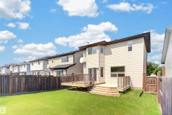 Expansive backyard featuring a manicured lawn, multi-level wood deck, privacy fence, and vinyl siding exterior - 