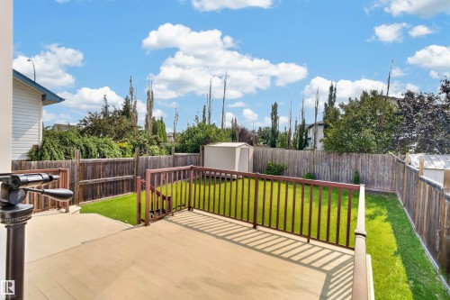 Expansive backyard featuring a wood-finish deck with railings, a manicured lawn, and a storage shed - 1707 37A Avenue Nw, Edmonton, AB - Outdoor