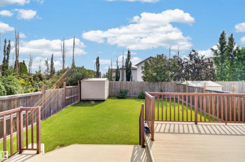 Expansive backyard featuring a wood-finish deck, full wood fencing, a storage shed, and a manicured lawn - 1707 37A Avenue Nw, Edmonton, AB - Outdoor