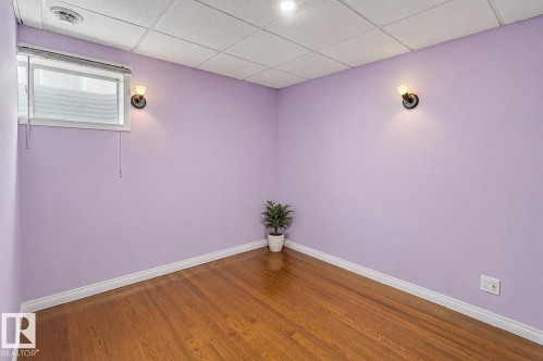 Hardwood flooring, painted walls, wall-mounted light fixtures, and a drop ceiling - 1707 37A Avenue Nw, Edmonton, AB - Indoor Photo Showing Other Room