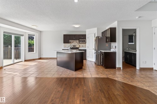 Kitchen with dark wood-finish cabinetry, stainless steel appliances, and a central island with a sink - 1707 37A Avenue Nw, Edmonton, AB - Indoor Photo Showing Kitchen